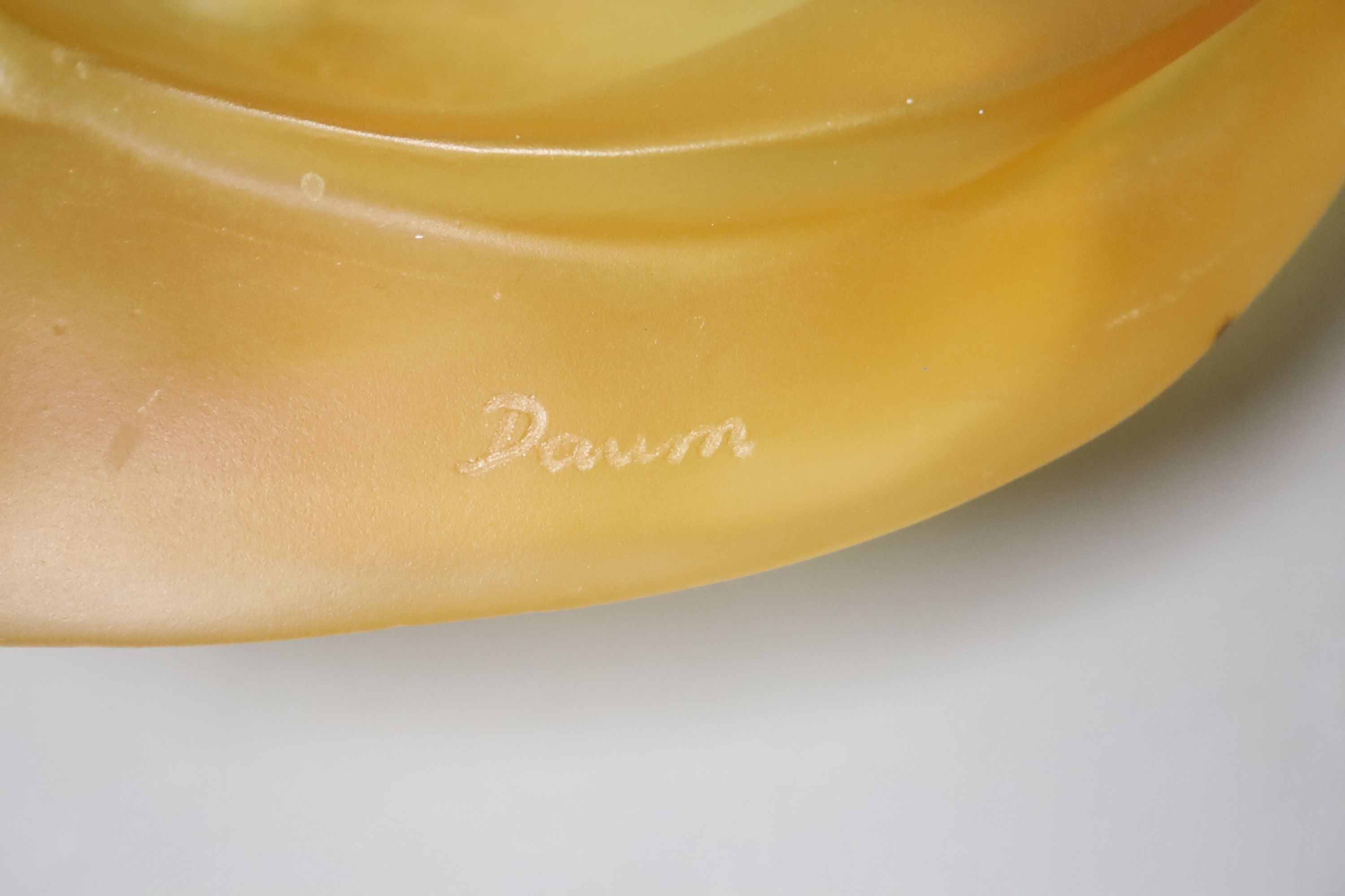 An amber glass dish with a recumbent lioness, signed, 24cm wide, apocryphal Daum mark